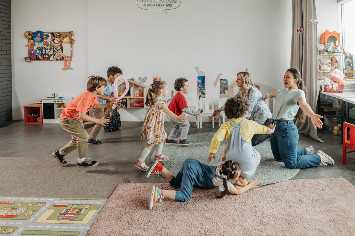 Staff kneeling on the floor with children in a classroom