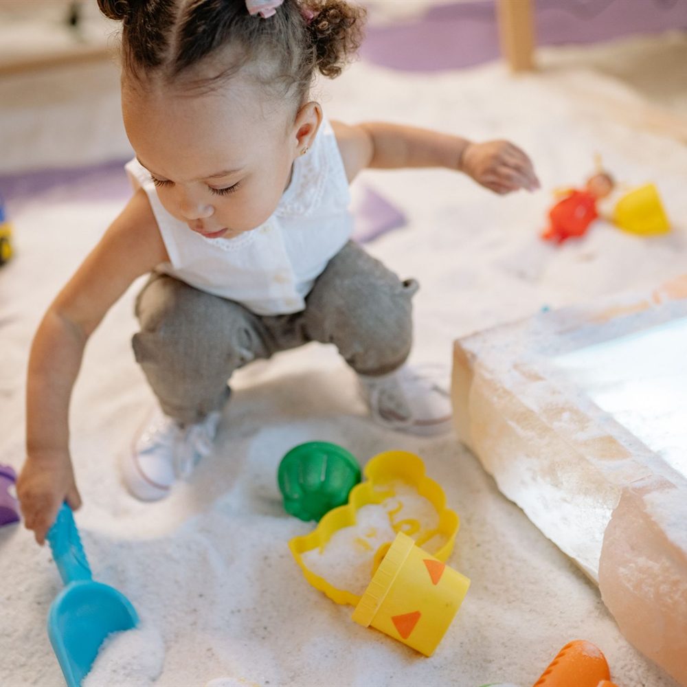 Child playing with a spade and moulds in the sandpit