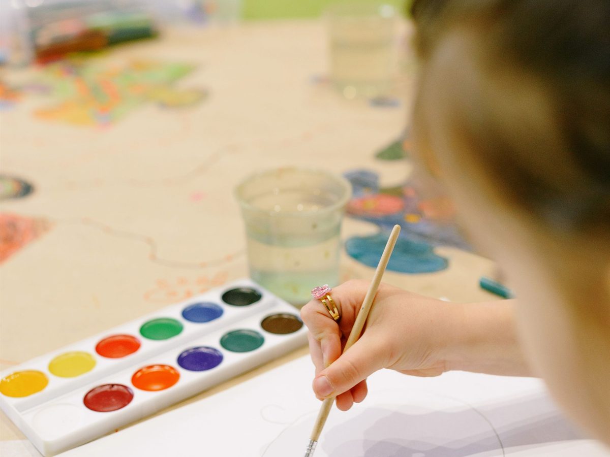 Young girl painting with a brush on white paper