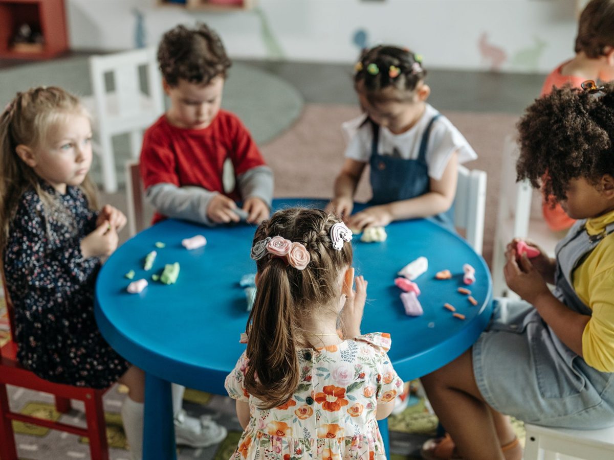 Toddlers working with playdough around a blue table